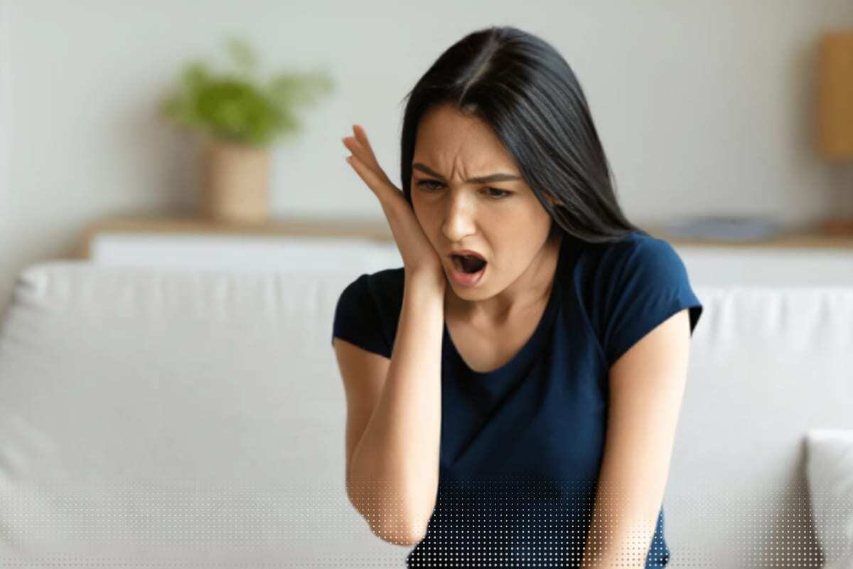 Woman with jaw pain holding her cheek, illustrating dental discomfort and implant sensitivity issues.